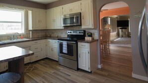 A kitchen with white cabinets, stainless steel appliances, and a wooden floor. - Manistee Channel Waterfront Home with Boat Dock (Manistee)