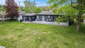 A two-story house with a covered patio area and a small deck. - Manistee Channel Waterfront Home with Boat Dock (Manistee)