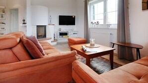 Uma sala de estar com lareira, televisão e janela com cortinas.