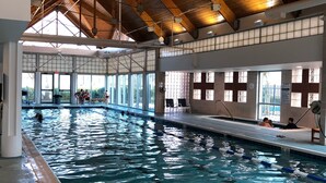 An indoor swimming pool with clear lanes, wooden beams on the ceiling, and large windows allowing natural light.
