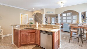 A spacious kitchen with granite countertops, wooden cabinets, and a dishwasher.
