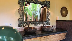 A bathroom with a large mirror, two sinks, and a decorative wall piece. - Rascals Boutique Kuta Lombok (Kuta)