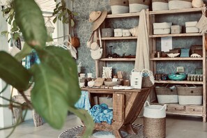 A rustic wooden table with baskets and storage boxes, surrounded by shelves with more baskets and decorative items. - Rascals Boutique Kuta Lombok (Kuta)