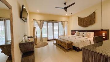 A hotel room with a large bed, a desk, a chair, a ceiling fan, and a large mirror.