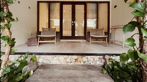 A covered porch with two wicker chairs, a stone wall, and a wooden bench. - Rascals Boutique Kuta Lombok (Kuta)