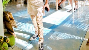 A person standing in a restaurant with a high ceiling, hanging lights, and a tiled floor. - Rascals Boutique Kuta Lombok (Kuta)