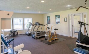 Een fitnessruimte met loopbanden, elliptische trainers en hometrainers.