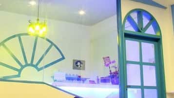 A room with a glass partition, a blue-framed window, a table with chairs, and a hanging light fixture.