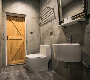 A bathroom with a wooden door, a toilet, and a sink with a mirror above it. - Lamanca B&B (Hualien City)