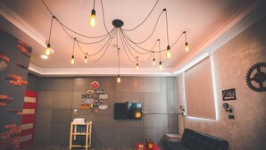 Una habitación con diseño moderno, que incluye un televisor montado en la pared, una escalera de madera y un sofá negro.
