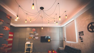 A room with a modern design, featuring a television mounted on the wall, a wooden ladder, and a black sofa.