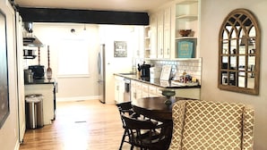 Una cocina amplia con piso de madera, un comedor con una silla estampada y vistas a través de un ventanal de arco.