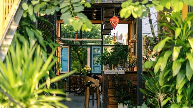 An indoor garden with wooden furniture and a sign that reads "Welcome to the Garden." - Trai Hoa Vang Homestay - Hostel (Phu Yen)