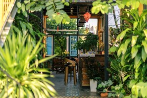 An indoor garden with wooden furniture and a sign that reads "Welcome to the Garden." - Trai Hoa Vang Homestay - Hostel (Phu Yen)