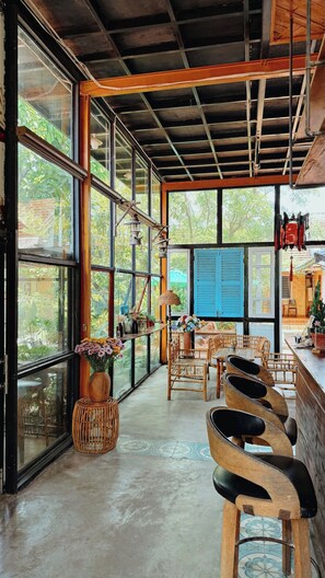 A spacious room with large windows, a high ceiling, and a rustic wooden ceiling.