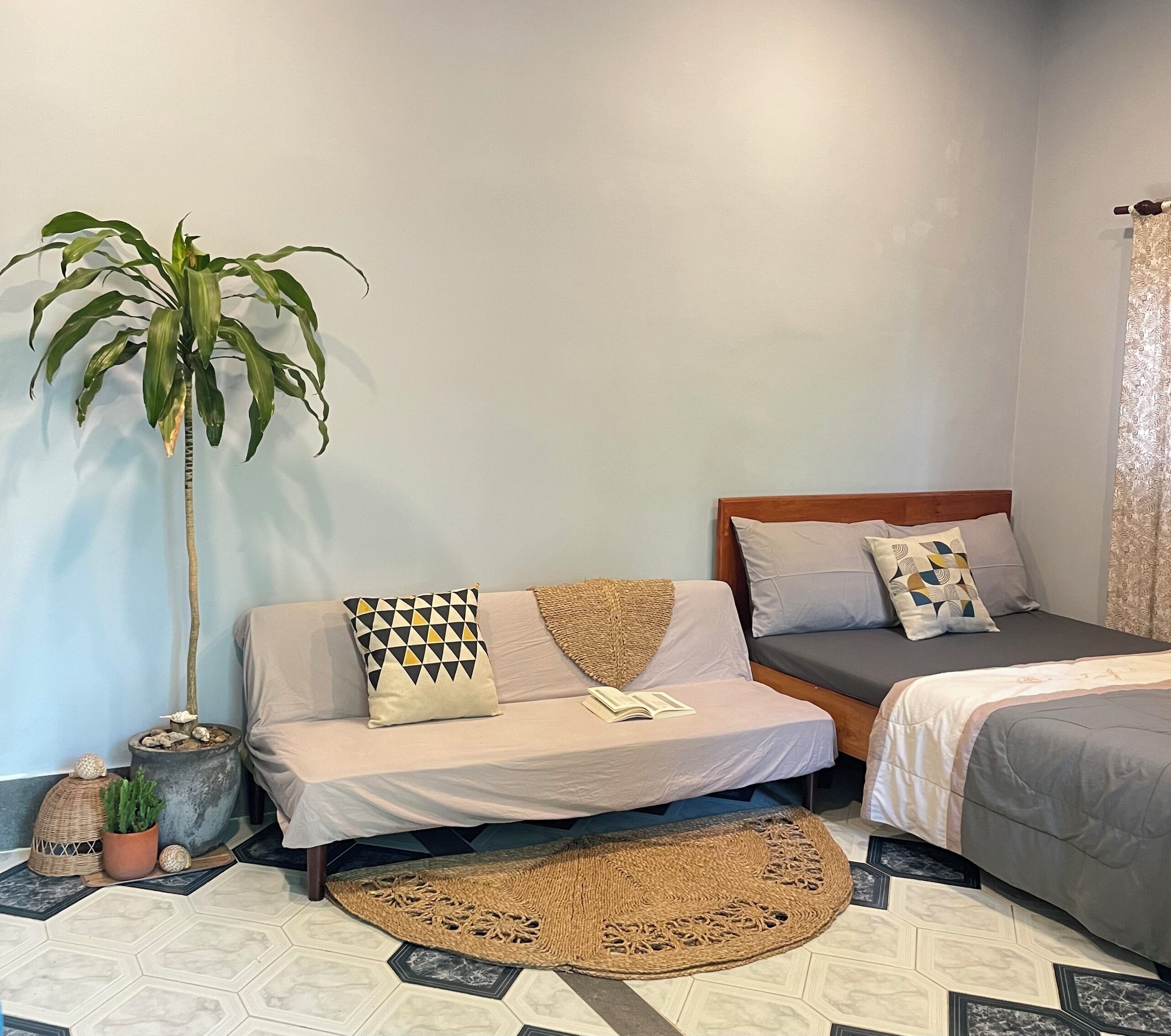A bedroom with a bed, a bedside table, a potted plant, and a rug.