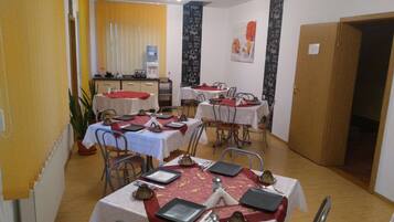 A dining area with multiple tables set for service, a water dispenser, and a coffee machine.