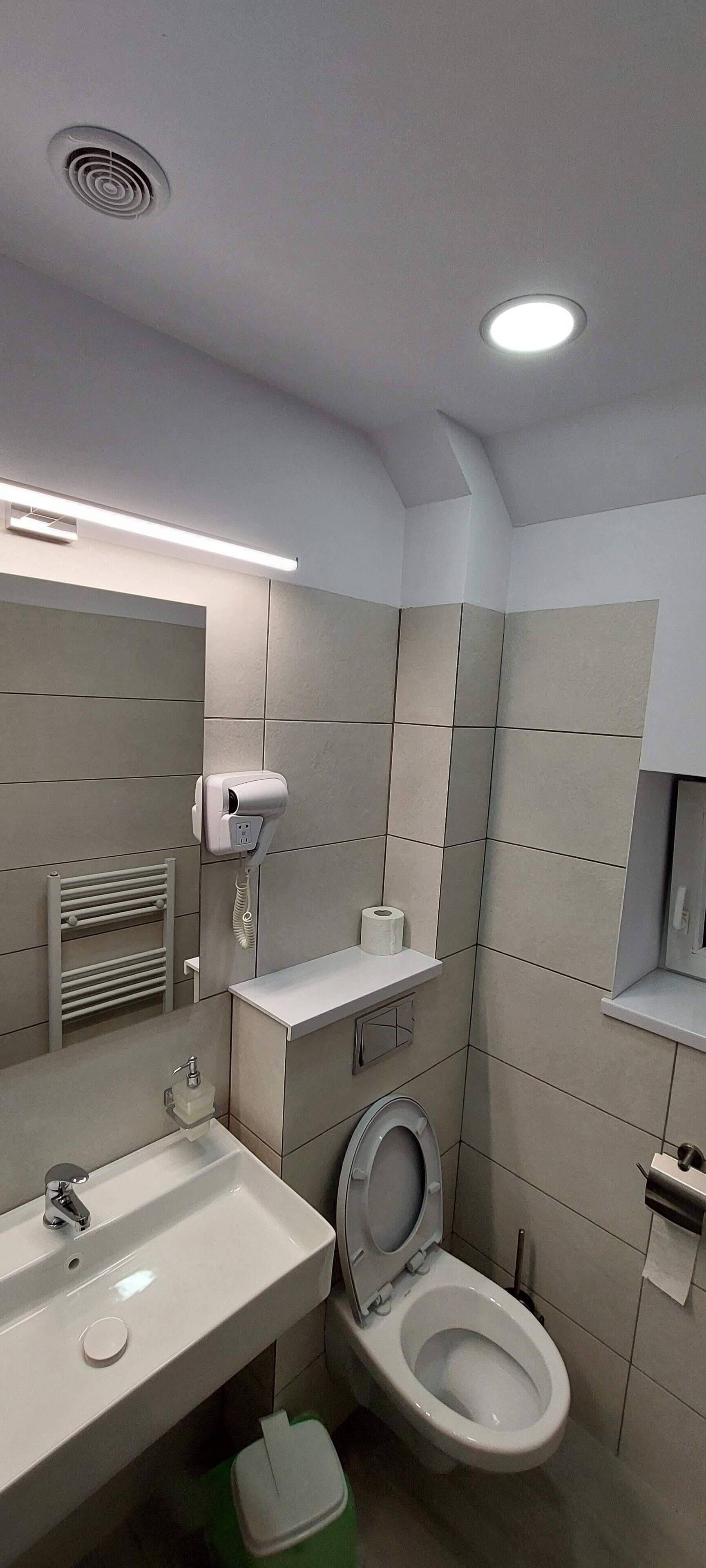 A modern bathroom with a sink, toilet, and towel rack.