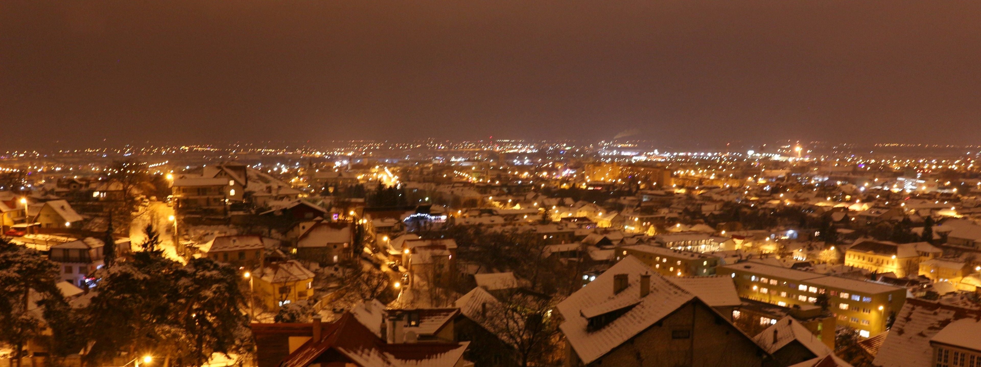 A nighttime view of a snow-covered town with illuminated buildings and streets.