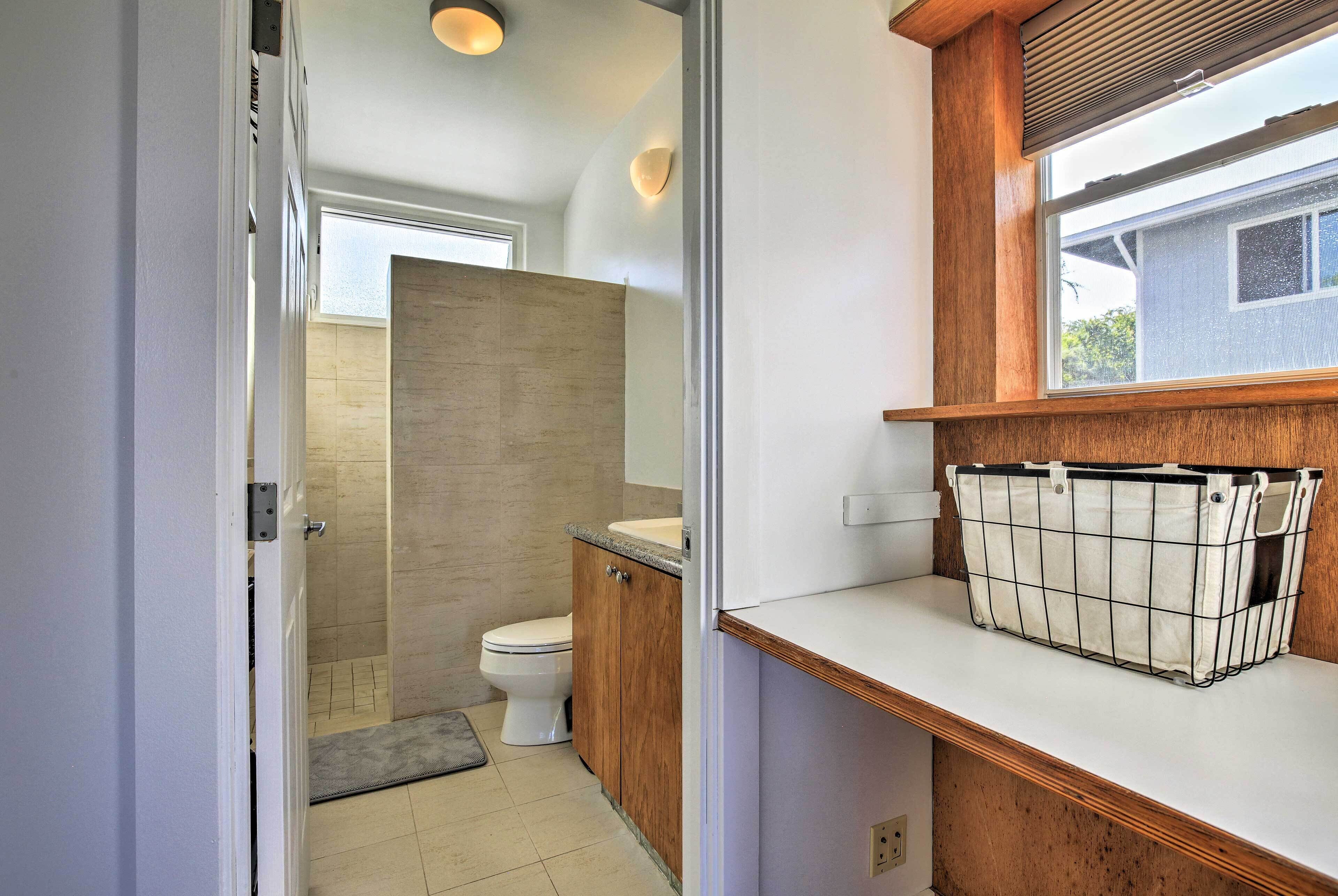A bathroom with a toilet, wooden cabinets, a towel rack, and a window.