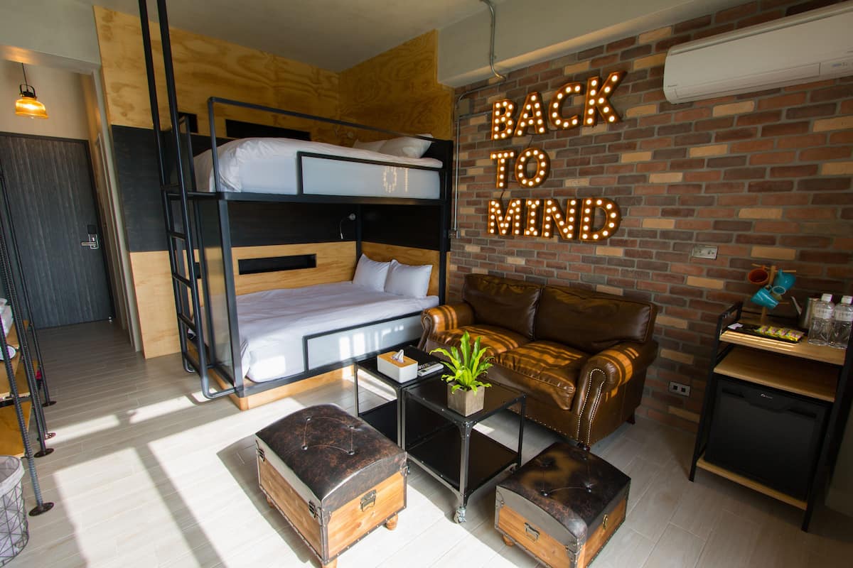 Une pièce chaleureuse avec des lits superposés, un canapé en cuir, une table basse et un mur orné d’un panneau lumineux portant l’inscription « BACK TO MIND ».