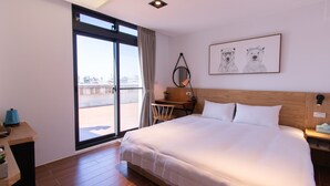 Habitación de hotel con una cama grande, un escritorio, una silla, un ventanal con vistas y un cuadro en la pared.