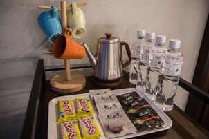 Una bandeja con aperitivos, una tetera y botellas de agua sobre una mesa.