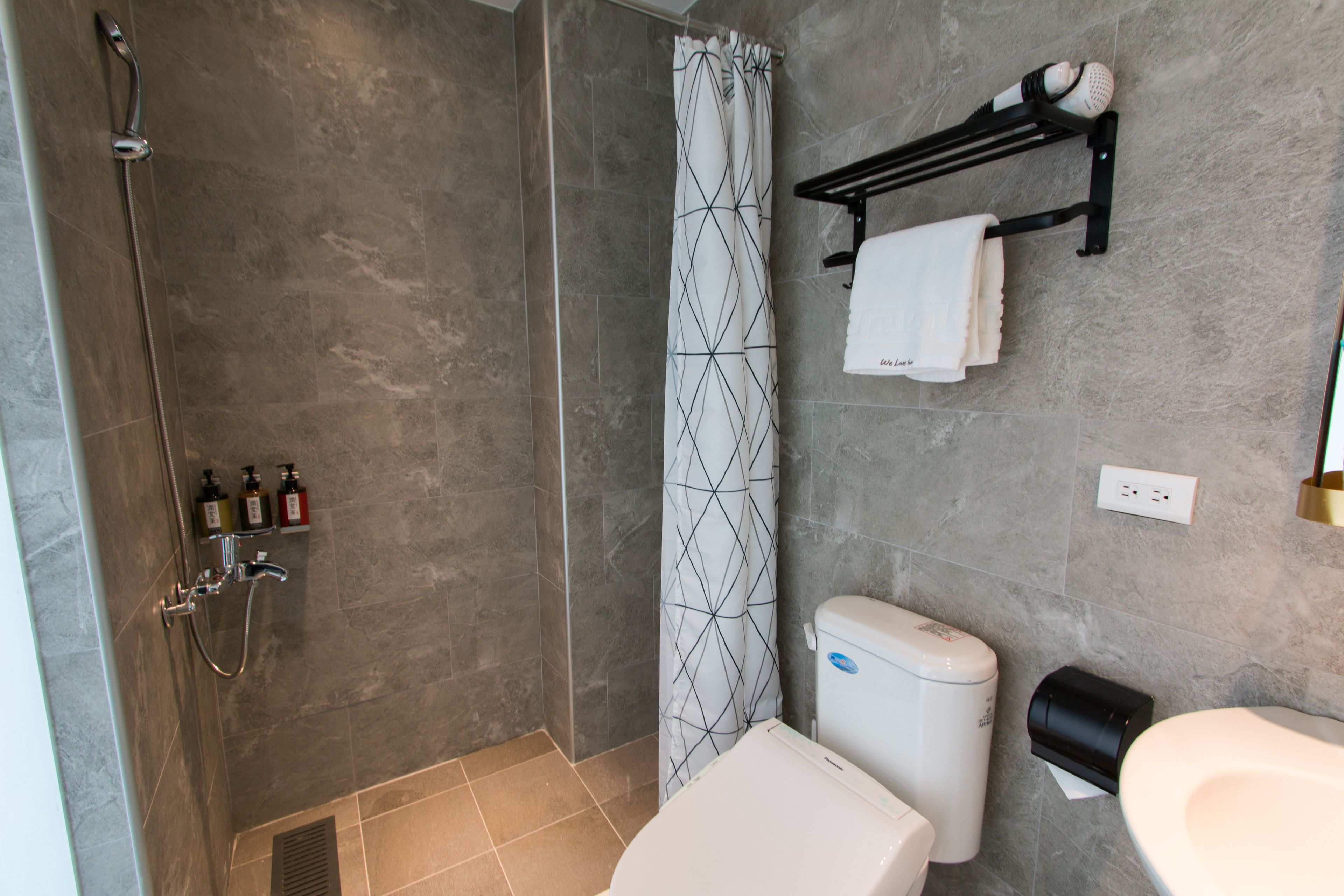 A modern bathroom with a shower, toilet, and towel rack.