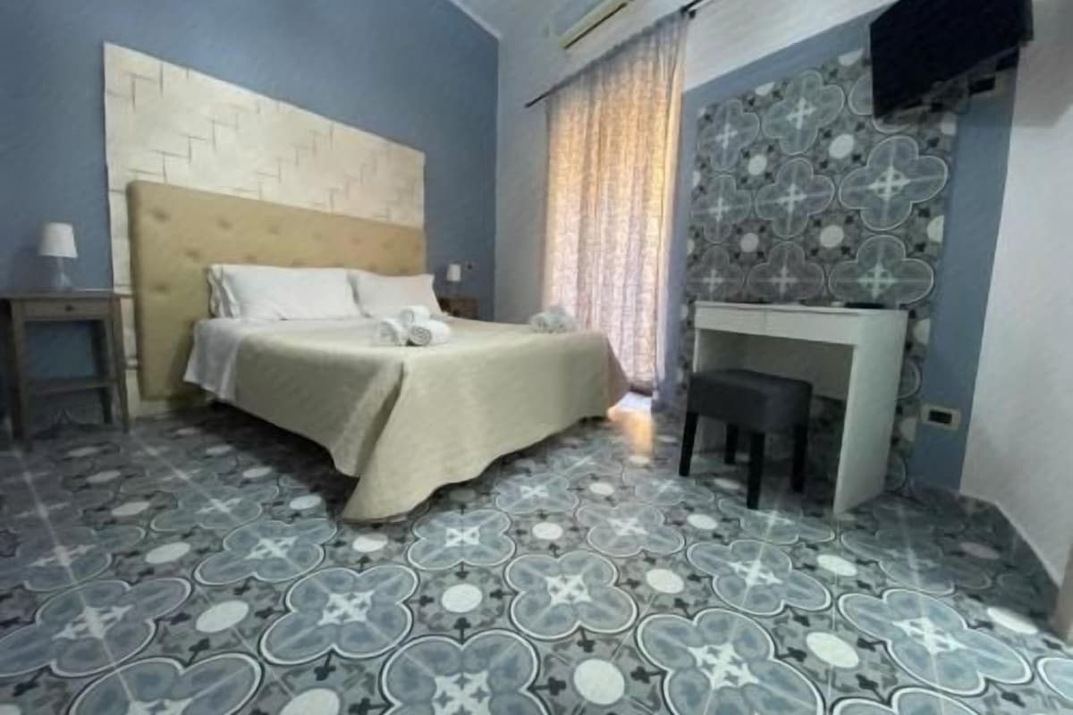 A bedroom with a bed, bedside table, and a desk with a chair.