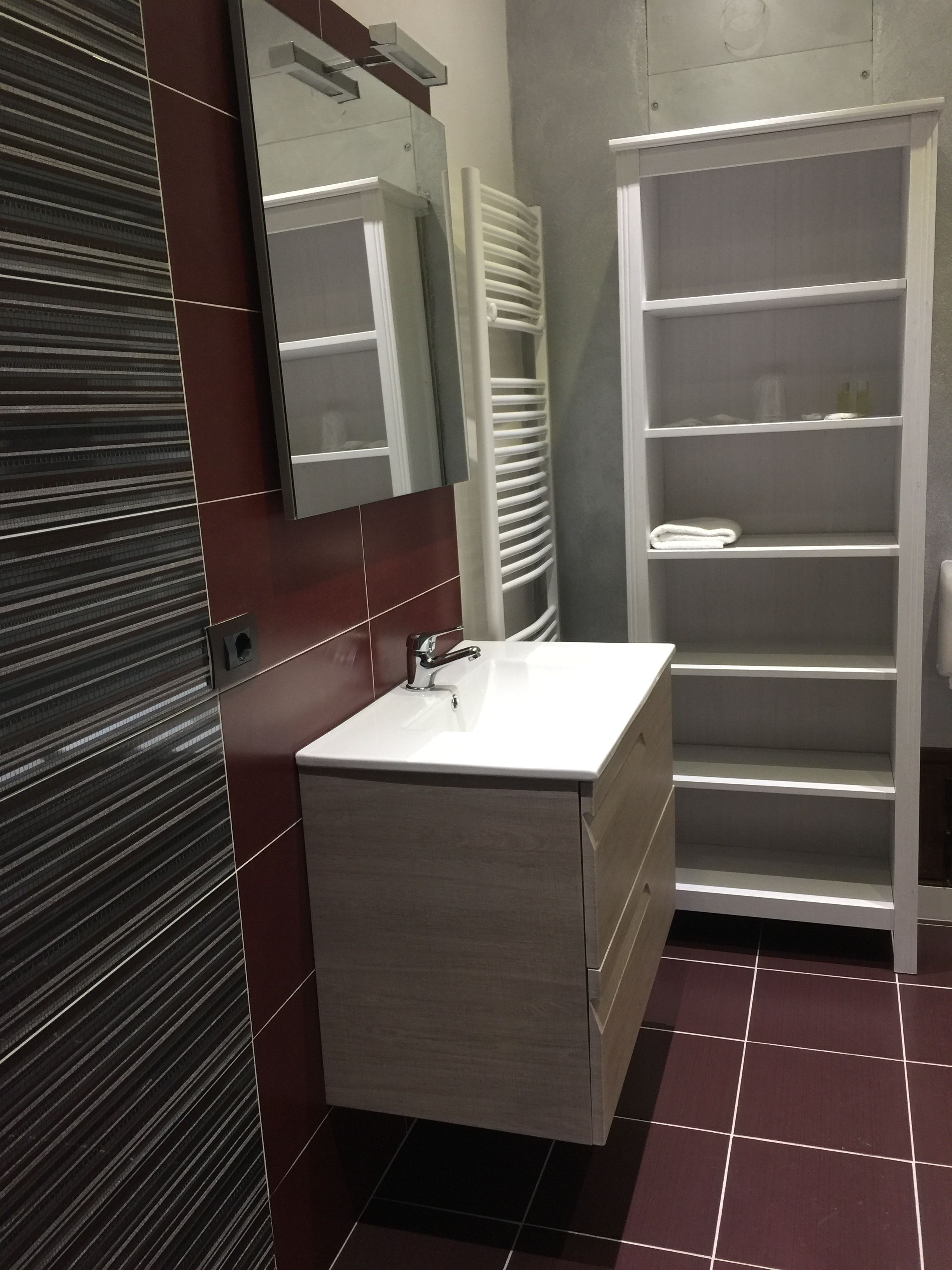 Ein modernes Badezimmer mit Waschbecken, Spiegel und weißem Handtuchhalter.