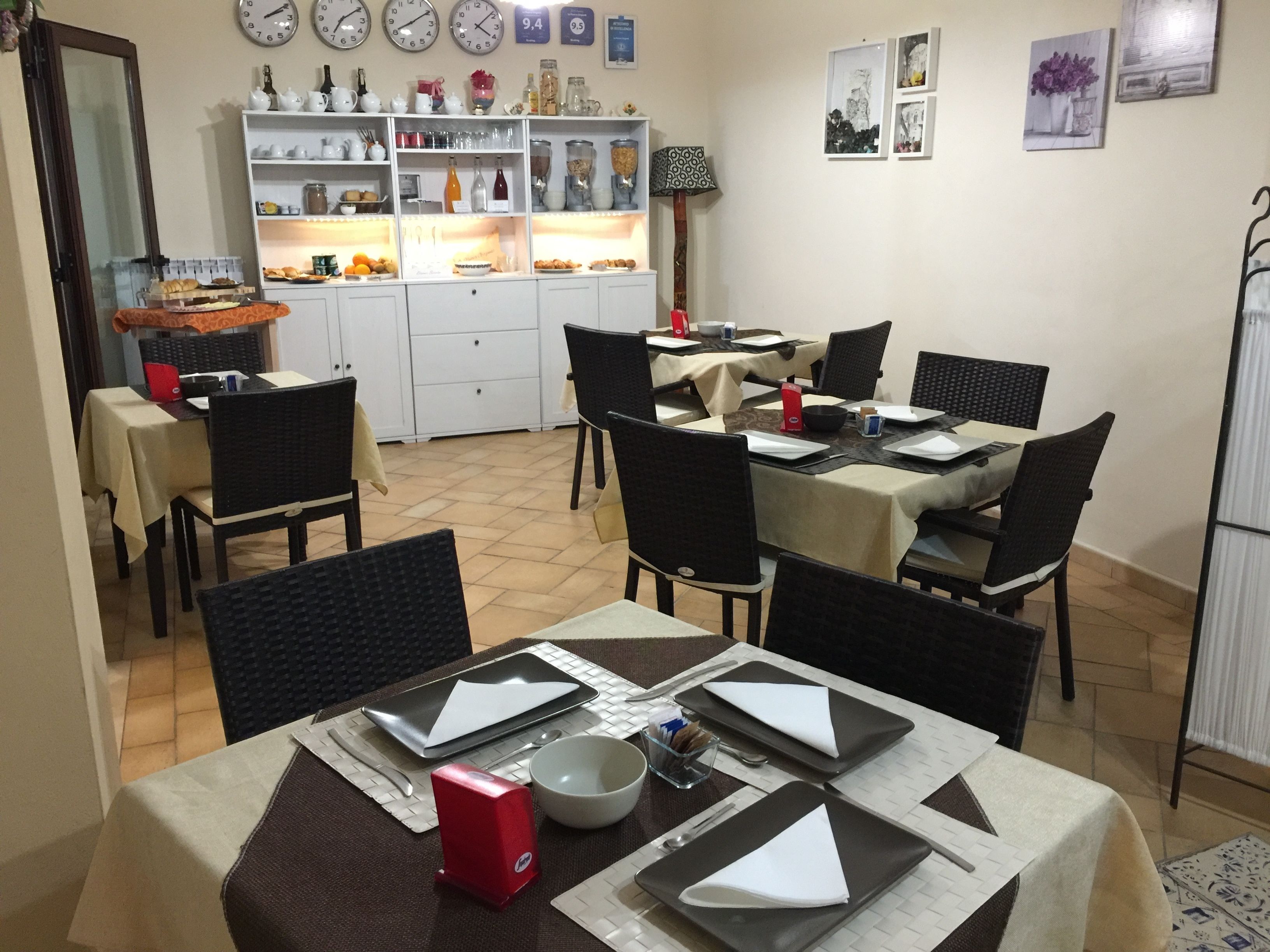A dining area with tables set for four, chairs, and a buffet line in the background.