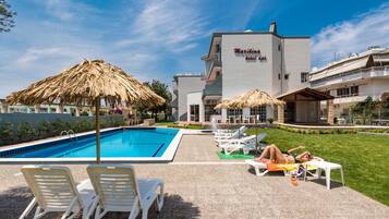 Una piscina al aire libre, sillones reclinables de piscina