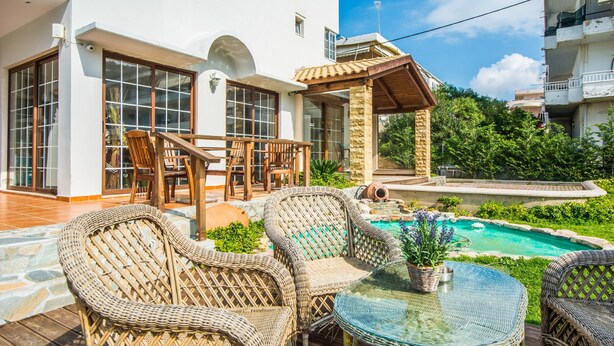 A patio with wicker furniture, a glass table, and a swimming pool. - Maritina Apartments (Rhodes)