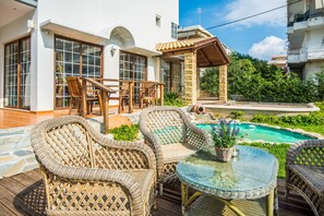 A patio with wicker furniture, a glass table, and a swimming pool. - Maritina Apartments (Rhodes)