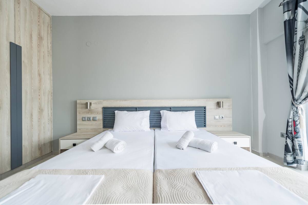 Un lit double avec du linge de lit blanc et deux oreillers, une tête de lit en bois et une table de chevet avec une lampe.