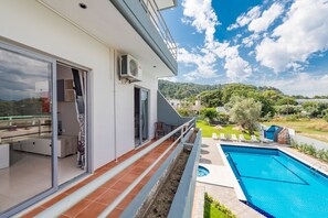 A modern house with a balcony overlooking a swimming pool and a lush green landscape. - Maritina Apartments (Rhodes)