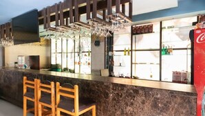 A bar area with a marble countertop, wooden chairs, and a Coca-Cola refrigerator. - Hotel Vassi Palaze (Chengalpattu)