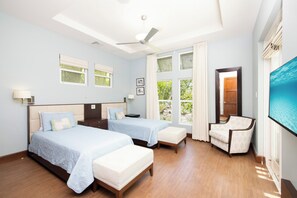 Ein Hotelzimmer mit zwei Betten, einem Fernseher, einem Sessel und Blick ins Freie.