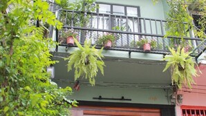 A hostel with a green facade, wooden doors, and a balcony with hanging plants. - Klong House Hostel (Bangkok)