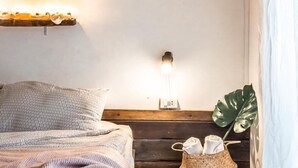 A bedroom with a bed, bedside lamp, macrame wall hanging, and a plant. - Klong House Hostel (Bangkok)