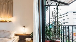 A balcony with a bed, a lamp, a wall-mounted macrame, and potted plants. - Klong House Hostel (Bangkok)