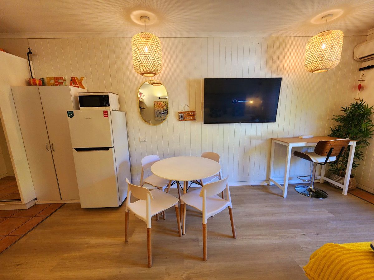 A compact living space with a dining area, a TV mounted on the wall, and a kitchenette.