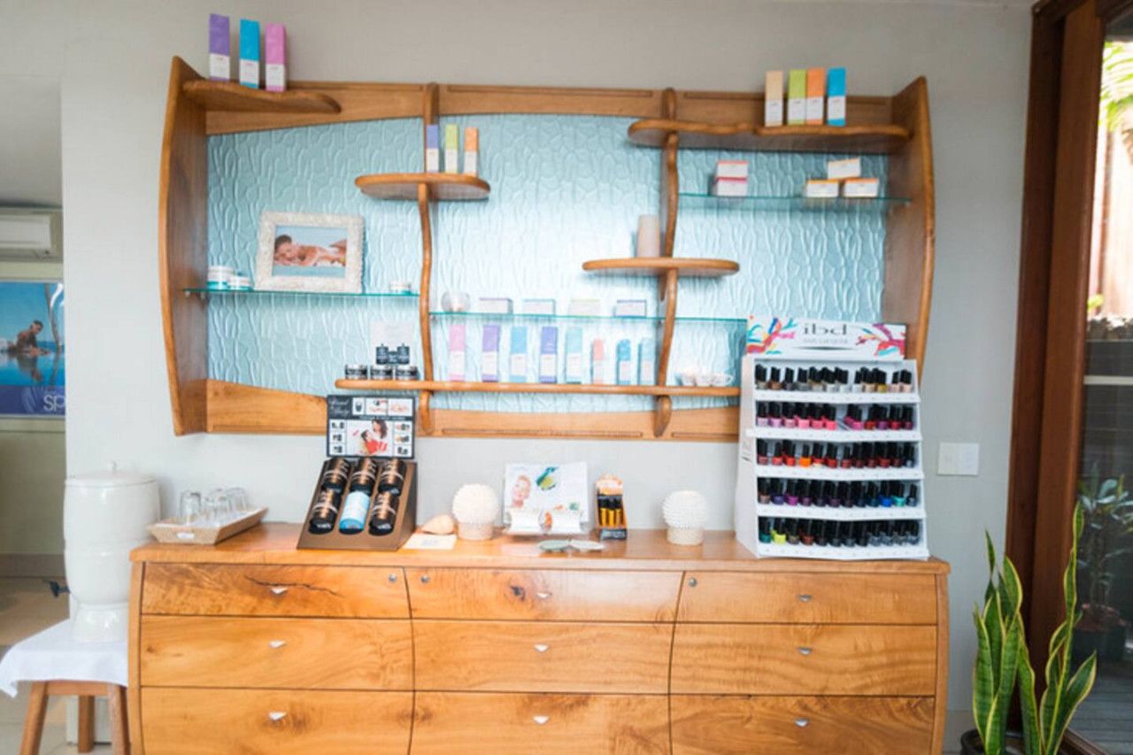 A reception desk with a wooden cabinet, glass shelves with various items, and a display of perfume bottles.