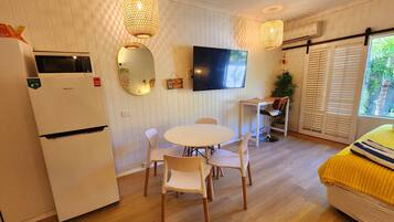 Un espacio habitable pequeño con kitchenette, una mesa de comedor redonda y un sofá.