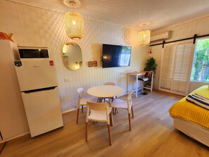 A compact living space with a kitchenette, a round dining table, and a sofa. - Ramada Resort & Spa, Deluxe Studio Apartment.! (Port Douglas)
