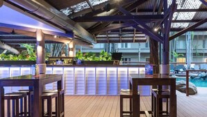An outdoor bar area with wooden flooring and seating, overlooking a pool. - - Private Holiday Apartment - In Ramada Resort- Port Douglas (Port Douglas)