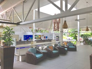 A spacious indoor area with wicker furniture and a reception desk. - Ramada Resort & Spa, Deluxe Studio Apartment.! (Port Douglas)