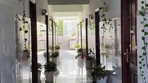 A hallway with potted plants, doors, and a tiled floor.