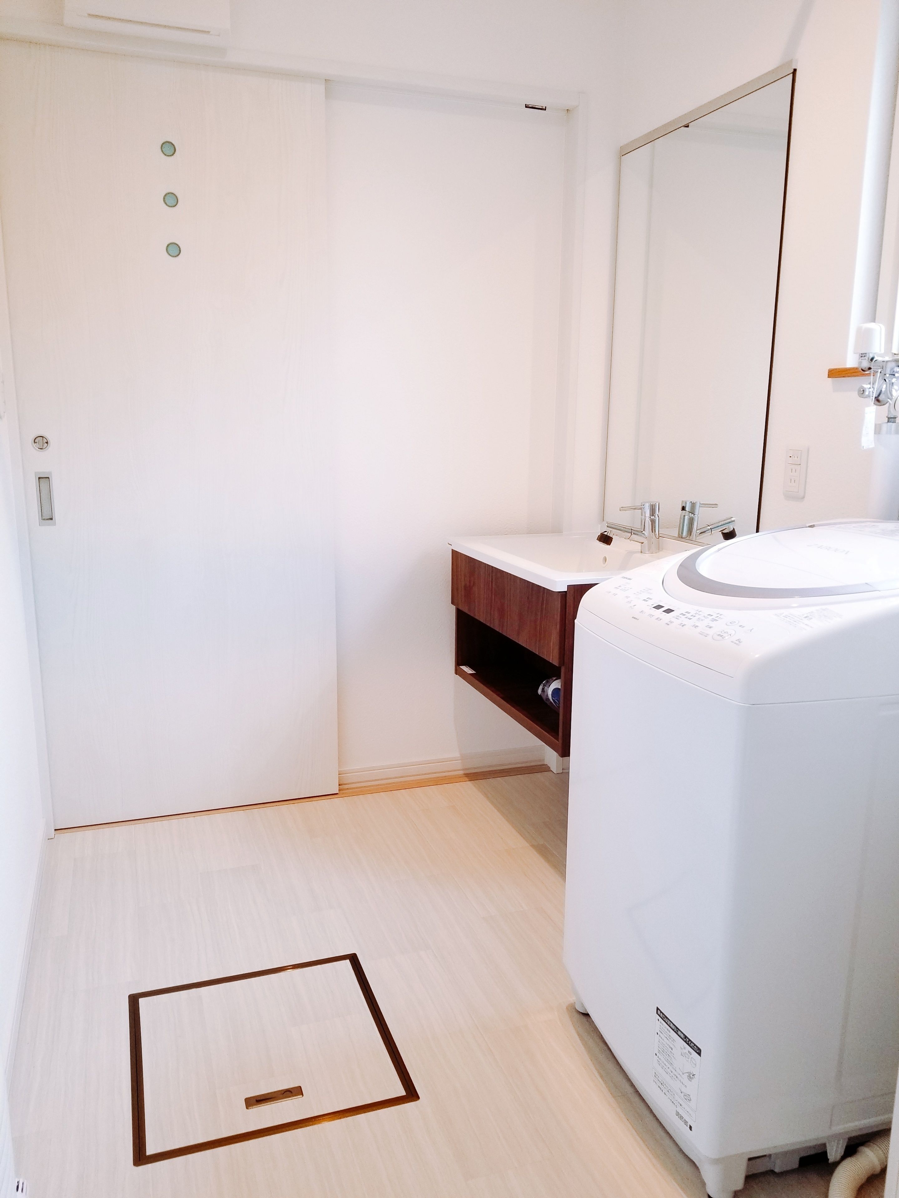 A bathroom with a white sink, mirror, and wooden vanity.