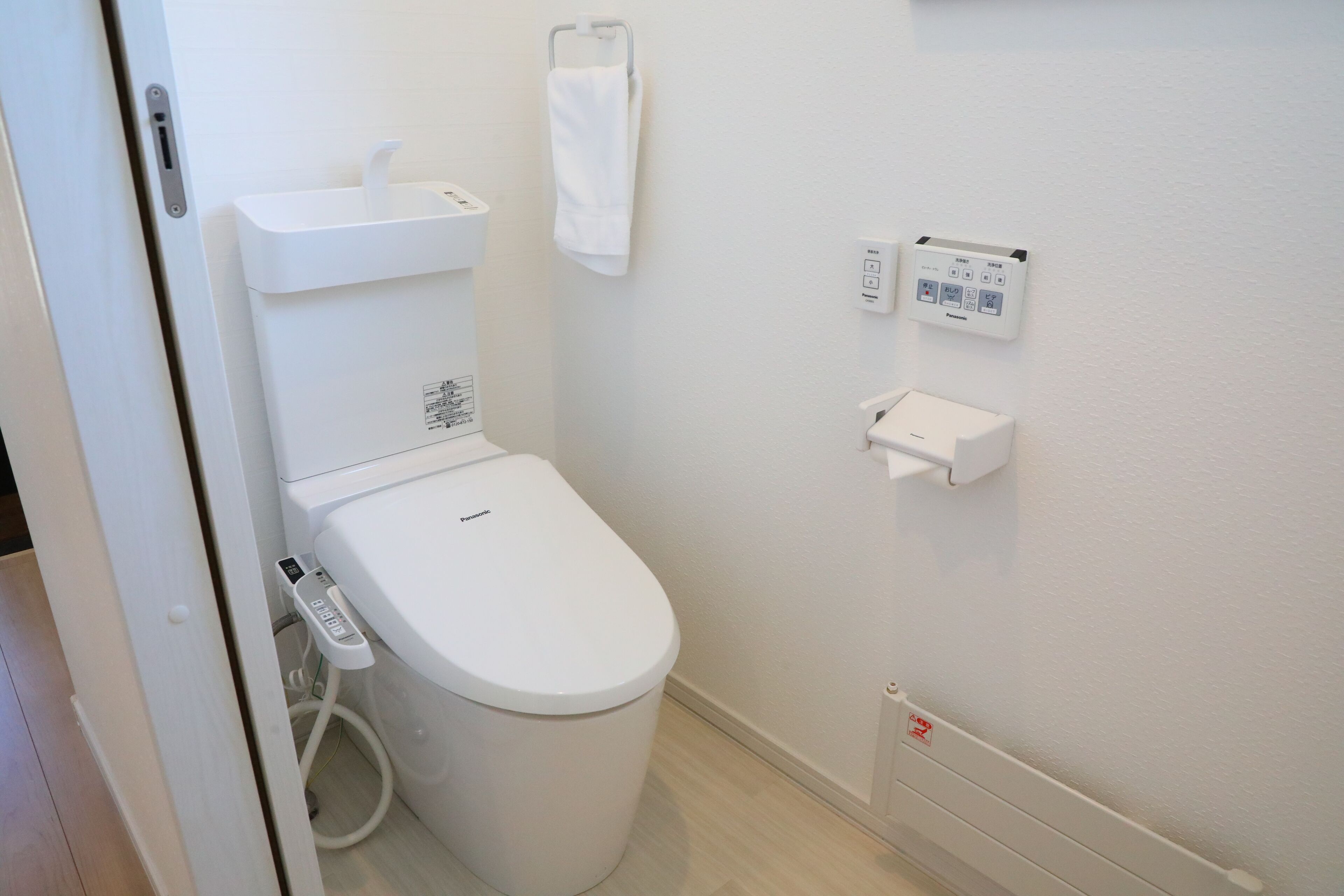 Une salle de bain moderne équipée de toilettes, d’un sèche-mains et d’un distributeur de serviettes en papier.
